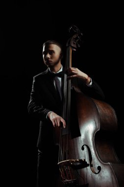 professional musician playing on contrabass isolated on black clipart