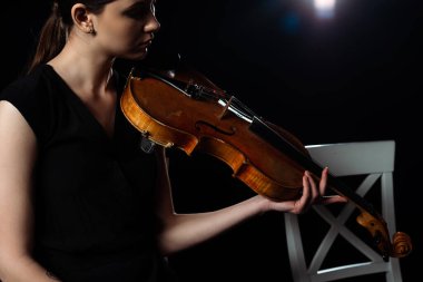 Güzel bayan müzisyen arka planda ışıkla keman çalıyor.