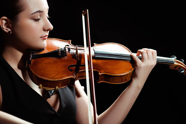 attractive female musician playing symphony on violin isolated on black