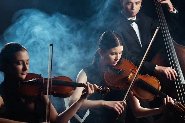 Trio Músicos Tocando Violinos Contrabando Palco Escuro Com Fumaça — Fotografia de Stock