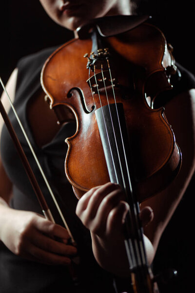 partial view of professional musician playing on violin isolated on black