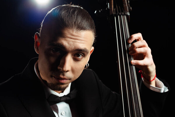 professional musician playing on double bass on dark stage