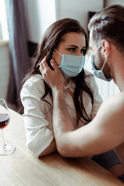 Pareja Joven Máscaras Médicas Mirándose Mesa —  Fotos de Stock