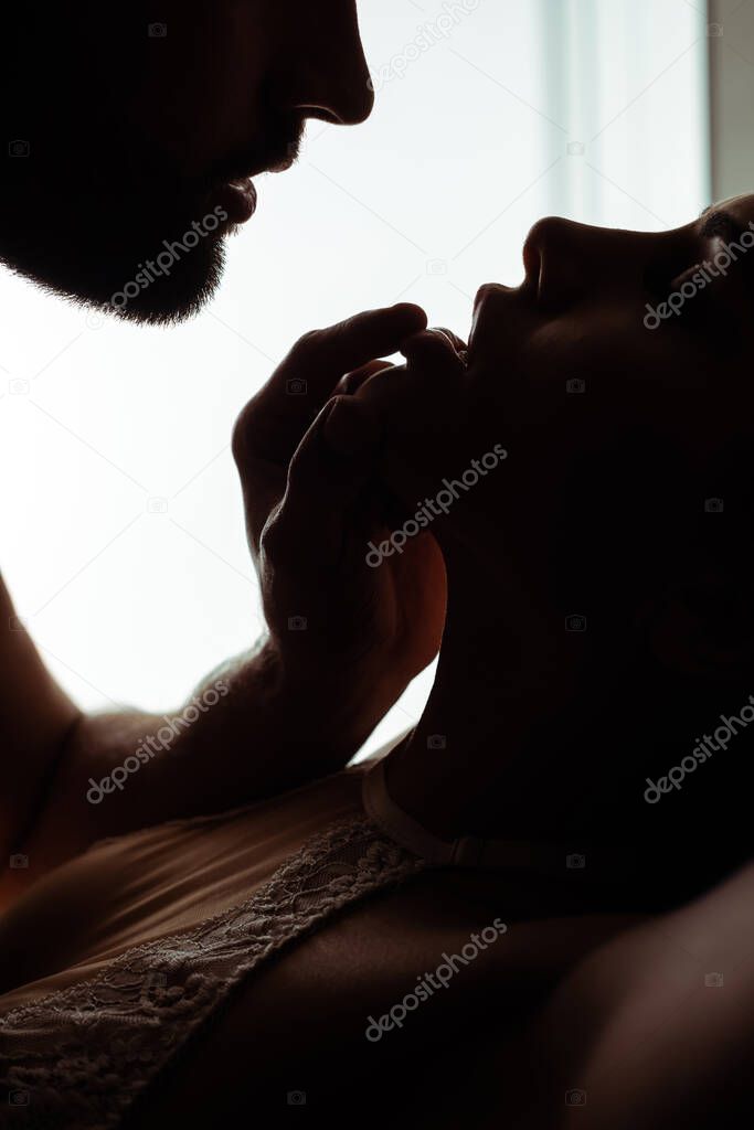 silhouettes of man touching lips of sexy young passionate woman