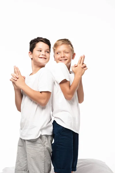 Two cheerful brothers standing back to back and showing gun gestures isolated on white — Stock Photo