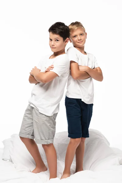 Two cunning boys standing back to back with crossed arms and smiling at camera isolated on white — Stock Photo