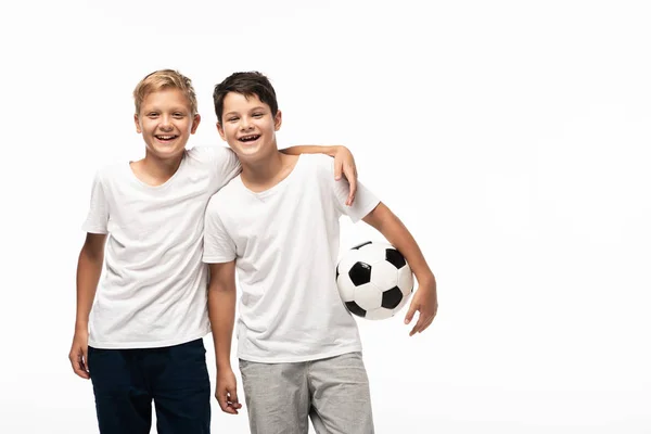 Menino feliz abraçando irmão segurando bola de futebol isolado no branco — Fotografia de Stock