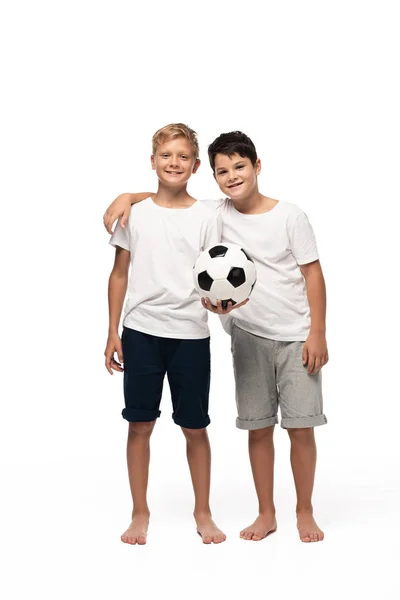 Cheerful boy hugging brother holding soccer ball on white background — Stock Photo