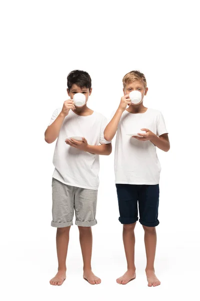 Two brothers looking at camera while drinking coffee on white background — Stock Photo