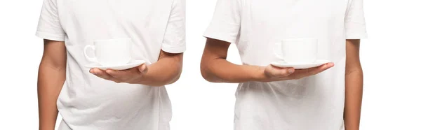 Vista recortada de dos niños sosteniendo platillos con tazas de café aislado en blanco, plano panorámico - foto de stock