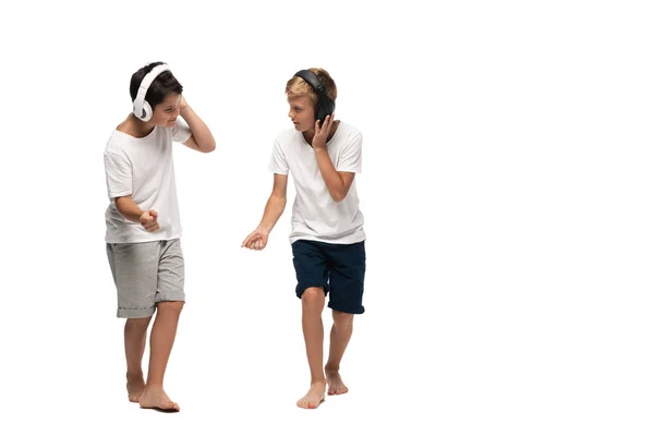 Dos hermanos escuchando música en auriculares y bailando sobre fondo blanco - foto de stock