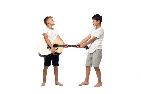 Two brothers looking at camera and dancing while listening music in headphones on white background — Stock Photo