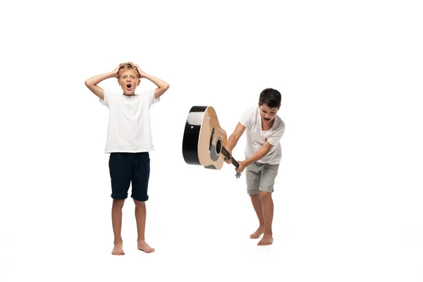 Dos hermanos mirando a la cámara y bailando mientras escuchan música en auriculares sobre fondo blanco - foto de stock