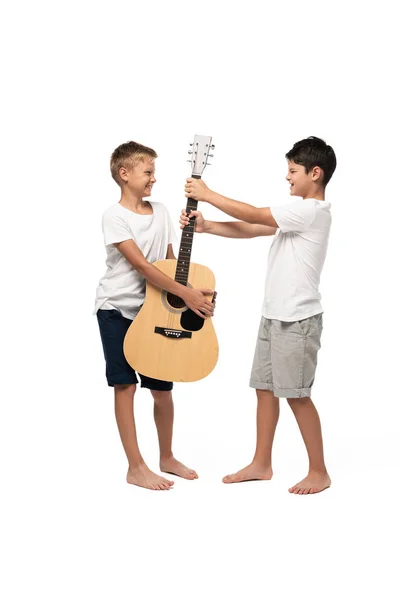 Непослушный мальчик забирает гитару у брата на белом фоне — стоковое фото