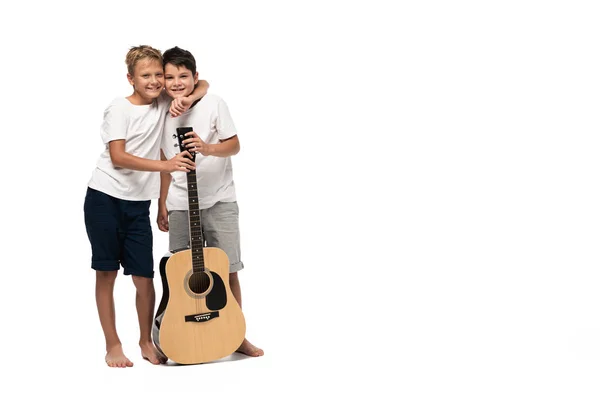 Dos hermanos mirando a la cámara y bailando mientras escuchan música en auriculares sobre fondo blanco - foto de stock
