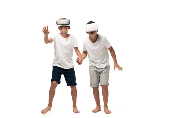 Dos hermanos mirando a la cámara y bailando mientras escuchan música en auriculares sobre fondo blanco - foto de stock