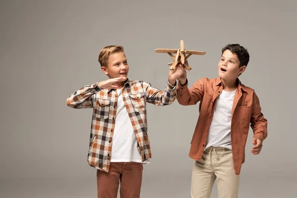 Two excited brothers playing with toy plane isolated on grey — Stock Photo