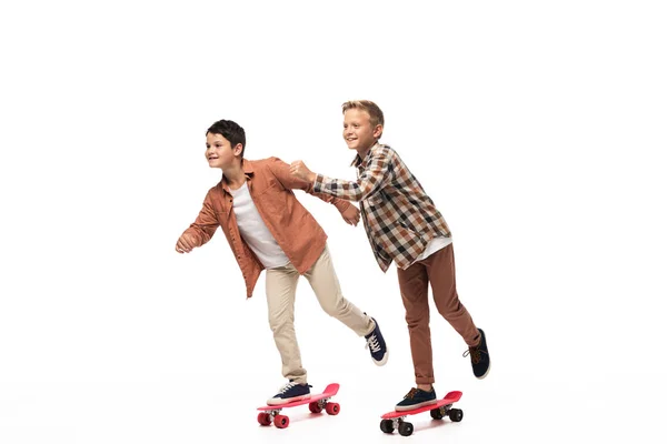 Dois irmãos felizes montando tábuas de centavo no fundo branco — Fotografia de Stock