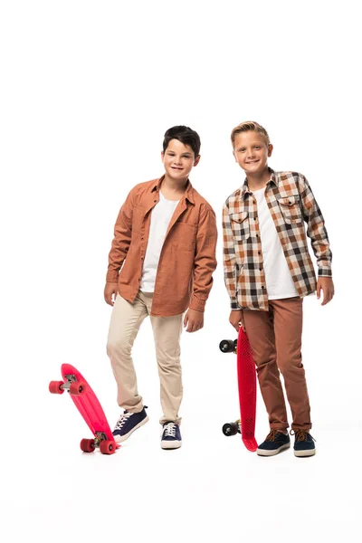 Two cheerful brothers with penny boards looking at camera on white background — Stock Photo