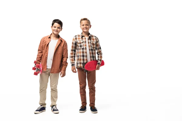 Deux frères souriants tenant des penny poards et regardant la caméra sur fond blanc — Photo de stock