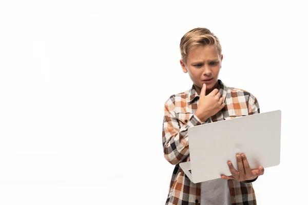 Thoughtful boy looking at laptop and holding hand near face isolated on white — Stock Photo