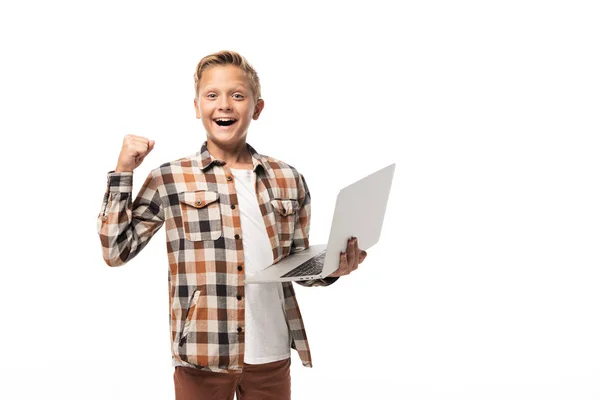 Alegre niño sosteniendo portátil, mostrando el gesto ganador y mirando a la cámara aislada en blanco - foto de stock