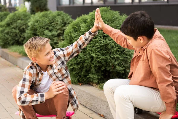 Two happy brothers giving high five while sitting on pavement — Stock Photo