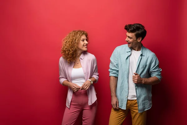 Beautiful smiling couple in casual clothes, isolated on red — Stock Photo