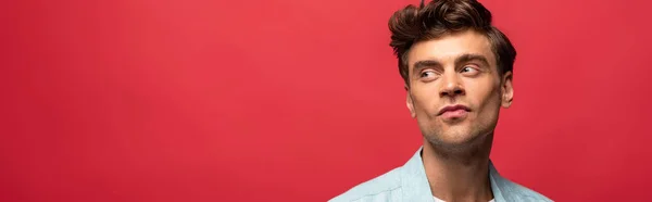 Portrait of handsome pensive man in casual clothes isolated on red — Stock Photo