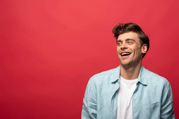 Retrato de belo homem rindo em roupas casuais isolado no vermelho — Fotografia de Stock