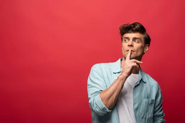 Retrato de belo homem pensativo em roupas casuais isolado no vermelho — Fotografia de Stock