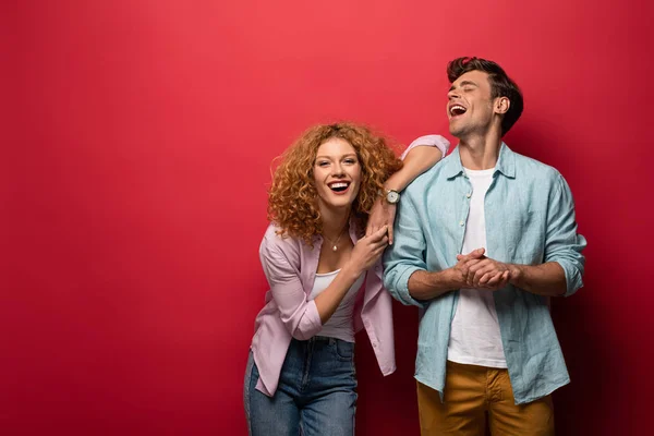 Beautiful laughing couple in casual clothes isolated on red — Stock Photo