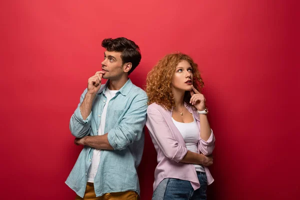 Beau couple coûteux penser et regarder vers le haut, isolé sur rouge — Photo de stock