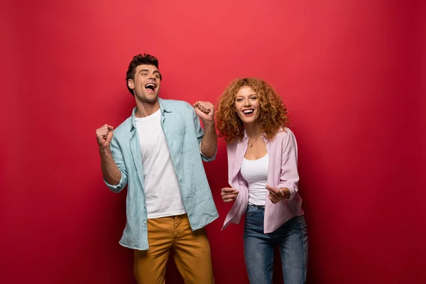 Beautiful excited couple in casual clothes isolated on red — Stock Photo