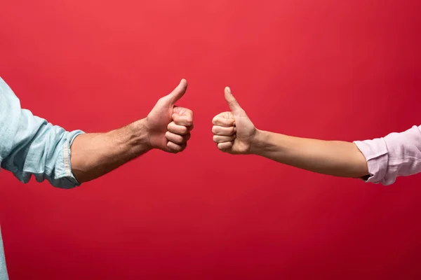 Partial view of couple showing thumbs up, isolated on red — Stock Photo