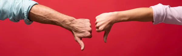 Partial view of couple showing thumbs down, isolated on red — Stock Photo