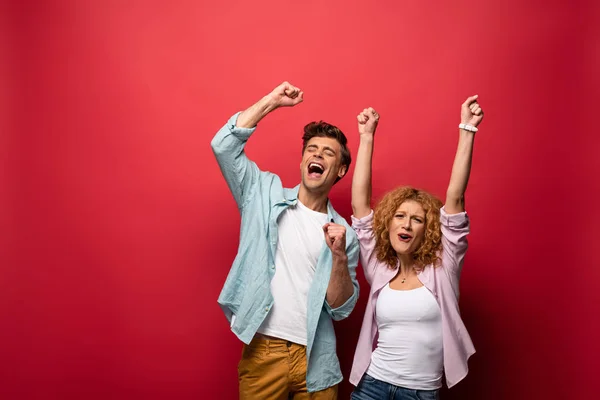 Excited young couple celebrating triumph, isolated on red — Stock Photo