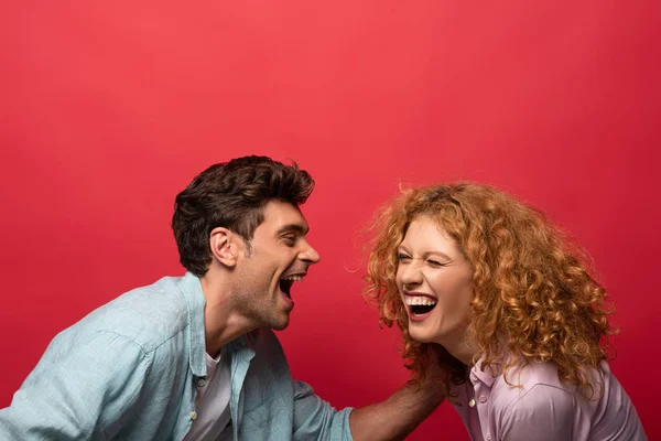 Beautiful happy couple laughing isolated on red — Stock Photo