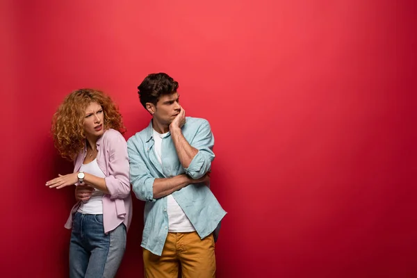 Belo casal preocupado em roupas casuais isolado no vermelho — Fotografia de Stock