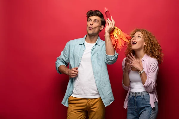 Excited beautiful couple throwing little rocket, on red — Stock Photo