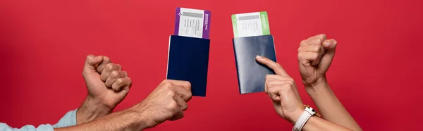 Partial view of couple holding fists and passports with air tickets, isolated on red — Stock Photo