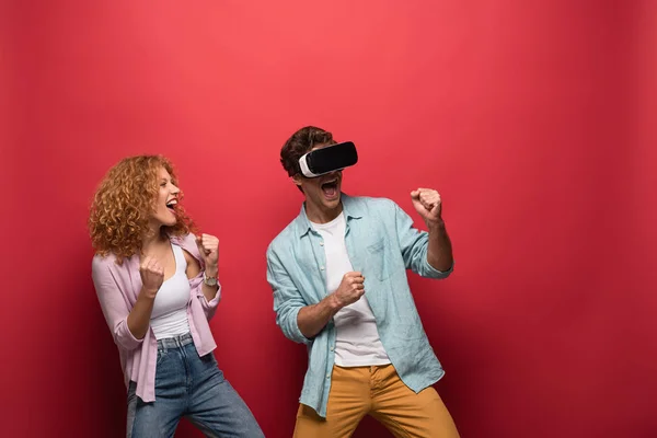 Belo casal animado em fone de ouvido realidade virtual, isolado no vermelho — Fotografia de Stock