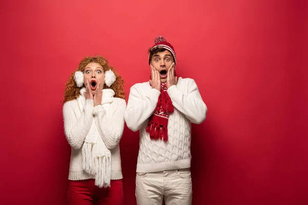 Belo casal chocado em roupa de inverno isolado no vermelho — Fotografia de Stock