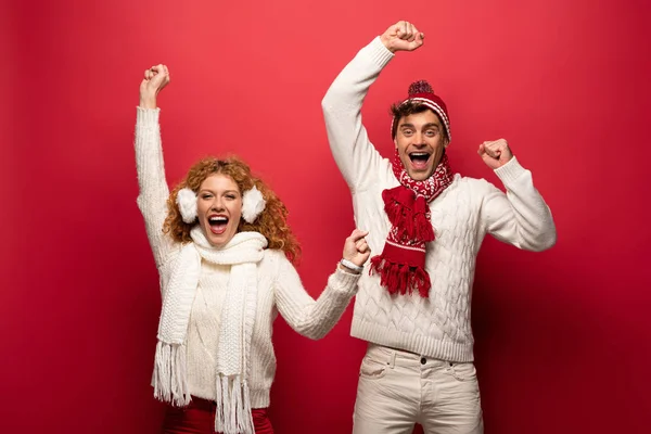 Casal animado em roupa de inverno gritando isolado no vermelho — Fotografia de Stock