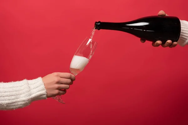 Cropped view of man pouring champagne from bottle into glasses, isolated on red — Stock Photo