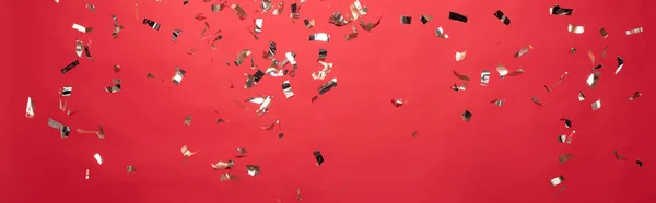 Panoramic shot of christmas golden confetti isolated on red — Stock Photo