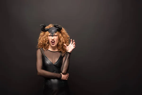 Gruselige Frau posiert im Halloween-Kostüm mit Hörnern auf Schwarz — Stockfoto