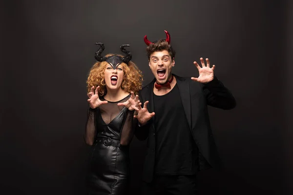 Effrayant jeune couple posant en costumes d'Halloween sur noir — Photo de stock