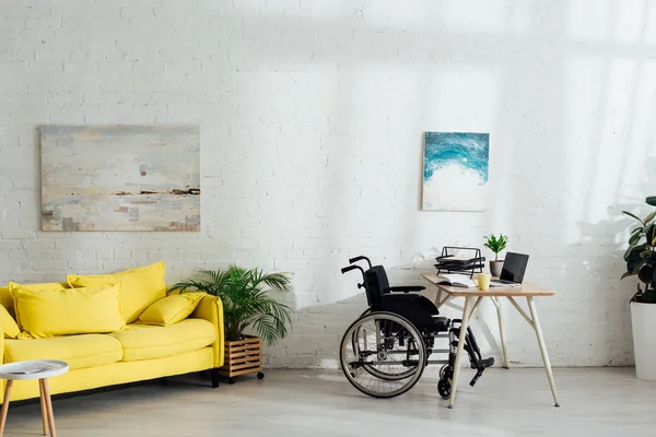 Intérieur du salon avec lieu de travail et fauteuil roulant par table — Photo de stock