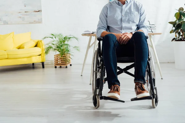 Обрізаний вид чоловіка, що сидить у інвалідному кріслі у вітальні — стокове фото